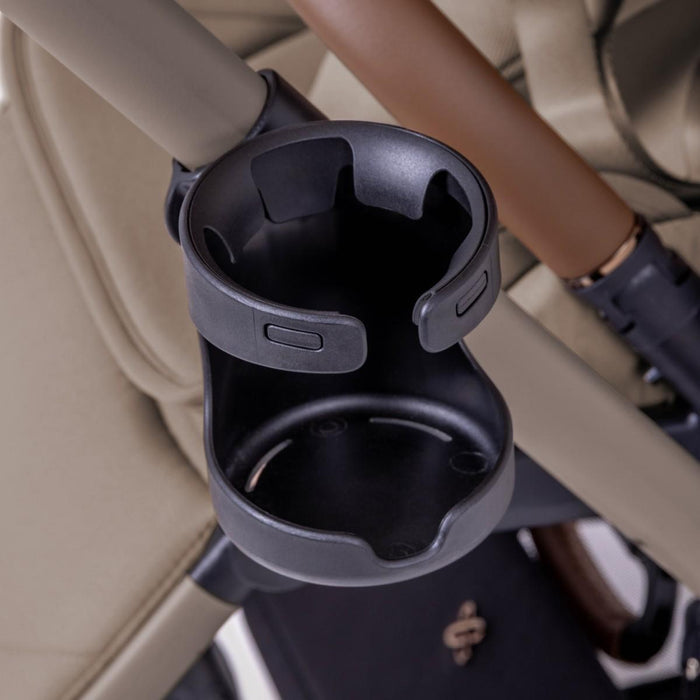 Close-up view of a black plastic cup holder attached to a stroller frame.