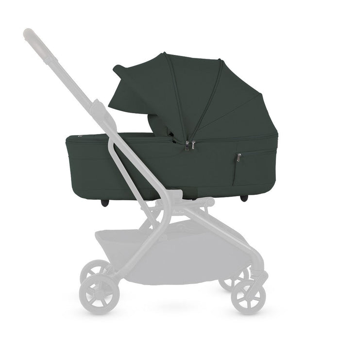 Side profile of a dark green stroller bassinet mounted on a faded stroller frame.