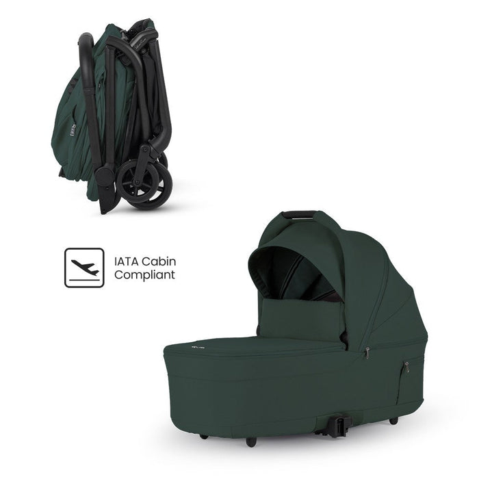 Dark green travel stroller shown compactly folded alongside a matching bassinet and an "IATA Cabin Compliant" logo.