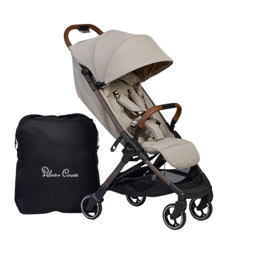 A lightweight tan stroller with brown leather trim standing next to its black fabric travel bag.