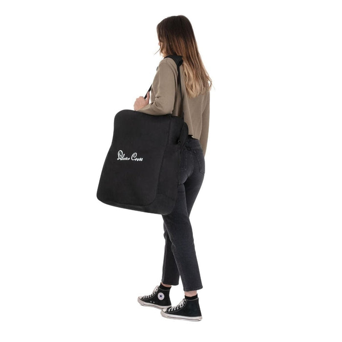 A woman carrying a black stroller travel bag over her shoulder.