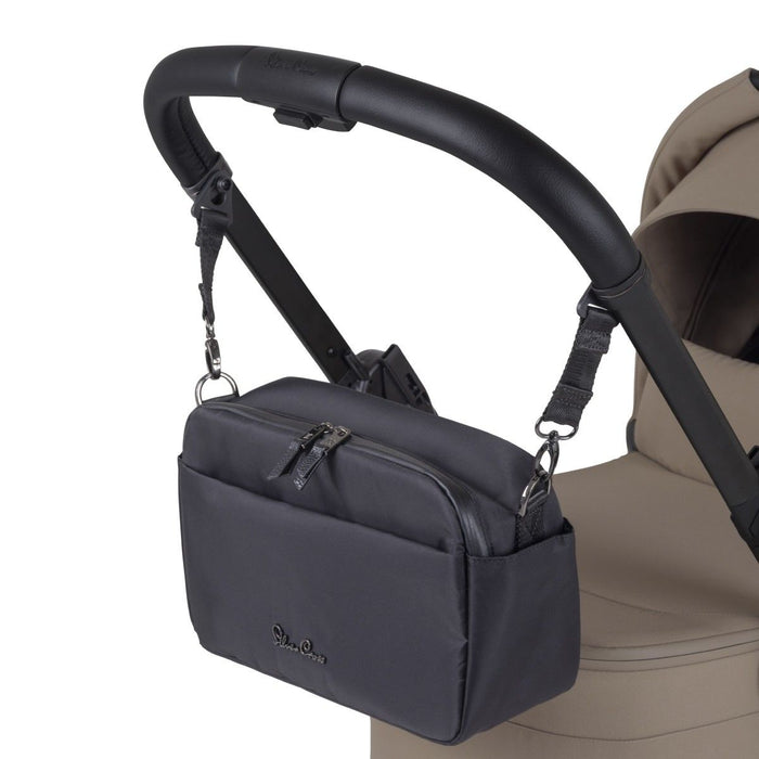 A black fabric stroller organizer bag hanging from a black leather handlebar by adjustable straps.