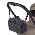 A black fabric stroller organizer bag hanging from a black leather handlebar by adjustable straps.