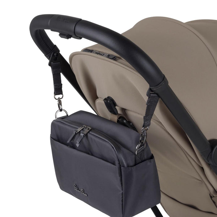 A black fabric stroller organizer bag hanging from a black leather handlebar by adjustable straps.